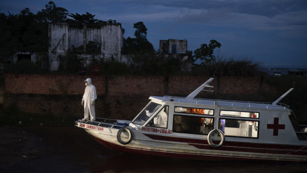 A health worker stands on a boat carrying COVID-19 patient Jose da Conceição as he waits for an ambulance to transfer him to a hospital after arriving in the port of Manacapuru, Amazonas state, Brazil.