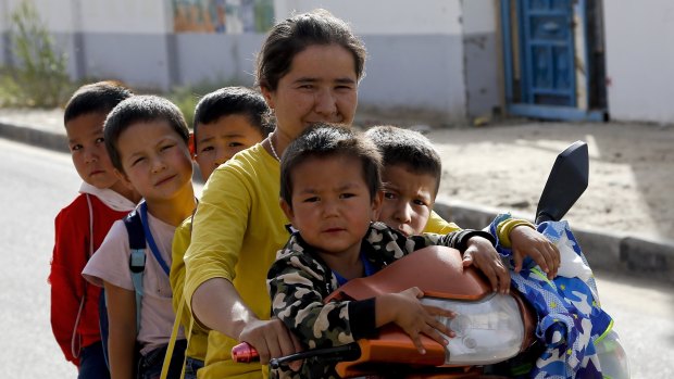 A Uighur woman and children sit on a motor-tricycle after school at the Unity New Village in Hotan, in western China's Xinjiang region. Birth rates in the mostly Uighur regions of Hotan and Kashgar have plunged  since 2015.