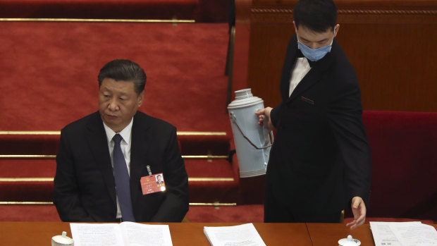 An attendant wearing a face mask to protect against the new coronavirus refills a cup next to Chinese President Xi Jinping. 
