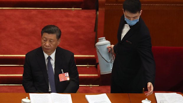 An attendant wearing a face mask to protect against the new coronavirus refills a cup next to Chinese President Xi Jinping. 