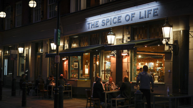 Customers sit in an outside area of a bar in Soho in London.