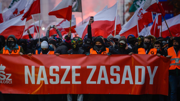 Members of far right hold red flares and Polish National flags during the Independence day march.