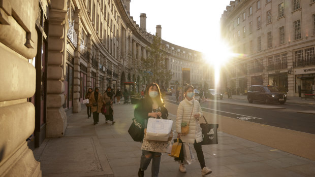 Pedestrians carrying shopping bags walk along Regents Street in London.