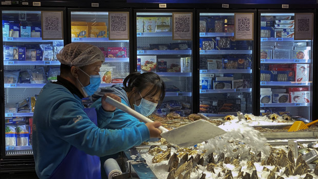 Workers shovel ice onto imported seafood at a Beijing supermarket.