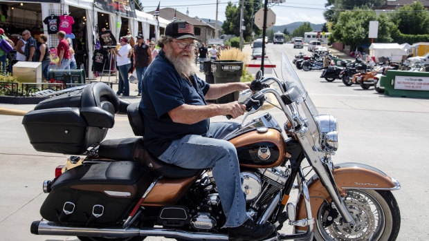A biker poses for a photo on Main Street during the 80th annual Sturgis Motorcycle Rally.