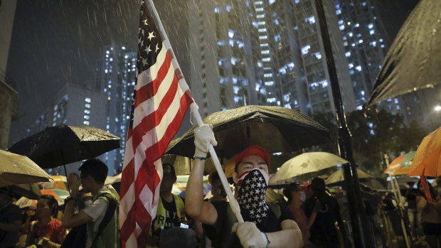 A protester waves a US flag as hundreds of protesters gather outside Kwai Chung police station in Hong Kong.