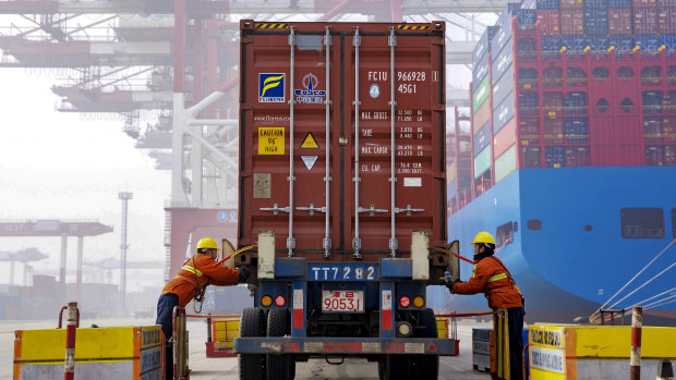Workers check on a container before loading it to a cargo ship at the Qingdao port in east China's Shandong province. 