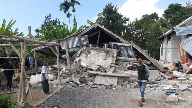 Villagers walk near destroyed homes in Lombok.