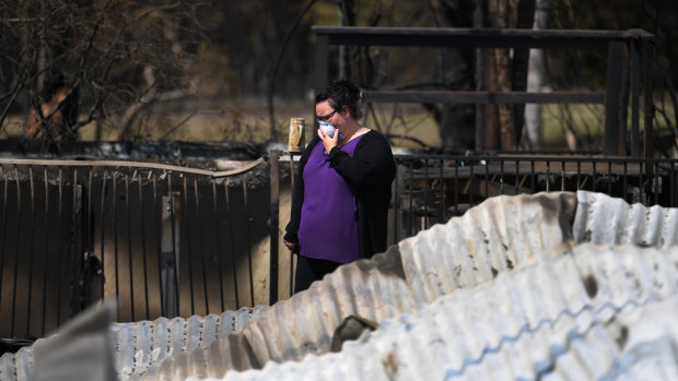 Naomi Elwell inspects the remains of her mother's house, which was destroyed by bushfires.