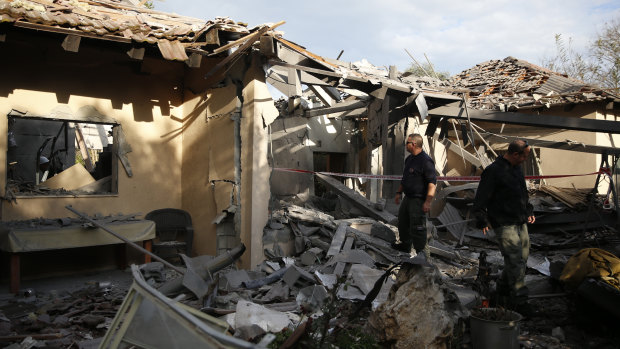 Police officers inspect the damage to a house hit by a rocket in Mishmeret, central Israel, on Monday.