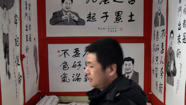 A man walks by posters featuring drawings of Chinese President Xi Jinping and his quotes, on display for sale at a market in Beijing.