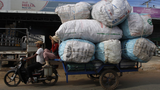 A couple transports sacks loaded with scrap materials into Phnom Penh, Cambodia