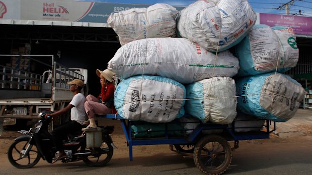 A couple transports sacks loaded with scrap materials into Phnom Penh, Cambodia