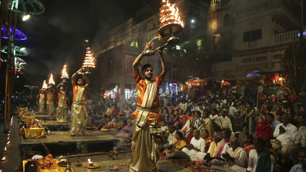 Devotees and tourists watch as Hindu priests perform daily rituals in reverence for river Ganges on its banks, in Varanasi, India, in March.