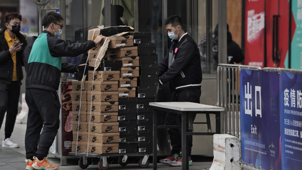 Workers push a cart loaded with Nike shoes past a security post at a shopping mall in Beijing last week.