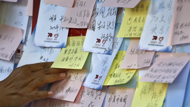 A woman places her note on a board near Tiananmen Square where visitors have been writing their wishes for the motherland ahead of the celebrations.