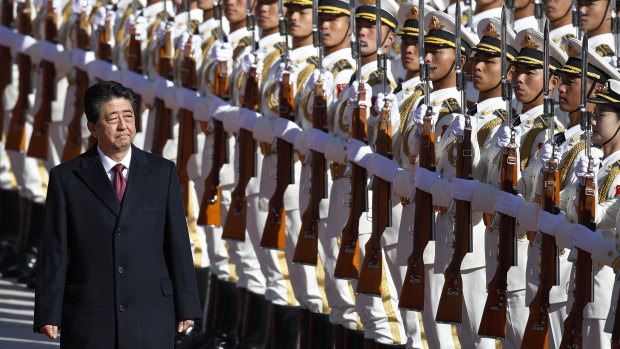 Japanese Prime Minister Shinzo Abe reviews an honor guard during a welcome ceremony at the Great Hall of the People in Beijing.