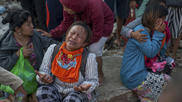 Residents react as a body of a tsunami victim is recovered in a village heavily damaged by Friday's tsunami in Palu.