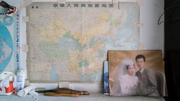 A wedding photo of Han's younger son is displayed in Han's living room/bedroom. The son's family migrated to Canada in 2003. 