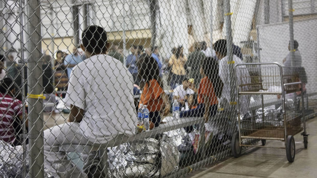 People taken into custody over  illegal entry into the United States sit in a cage in McAllen, Texas.