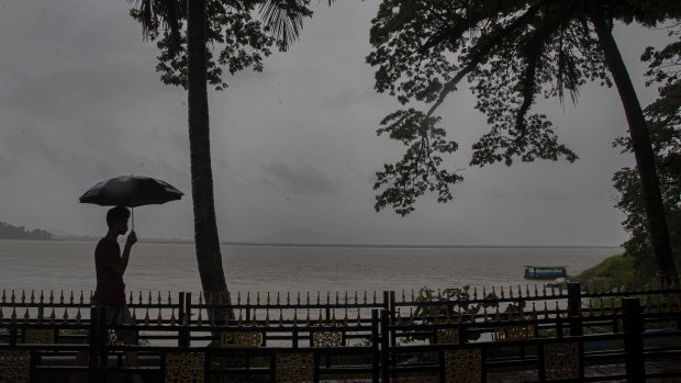 An Indian man walks with his umbrella in the middle of heavy wind and rain along the river Brahmaputra in Gauhati, India.