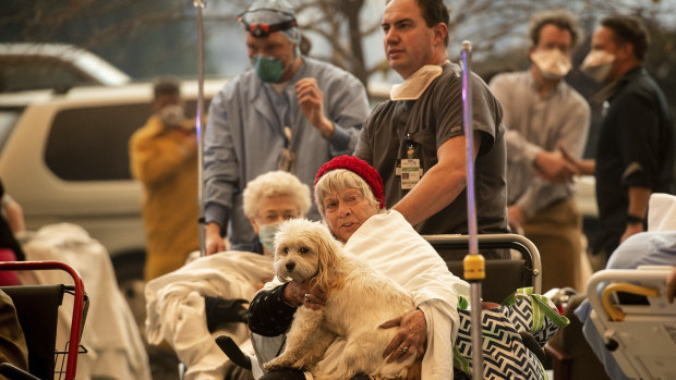 Medical personnel evacuate patients - one holding a pet dog - as the Feather River Hospital burns while the Camp Fire rages through Paradise, California.
