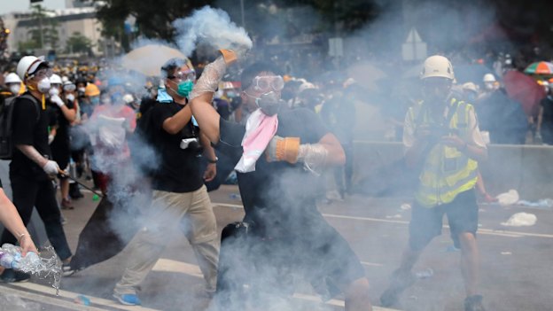 A demonstrator throws a canister of tear gas back at police during protests outside the Legislative Council on June 12.