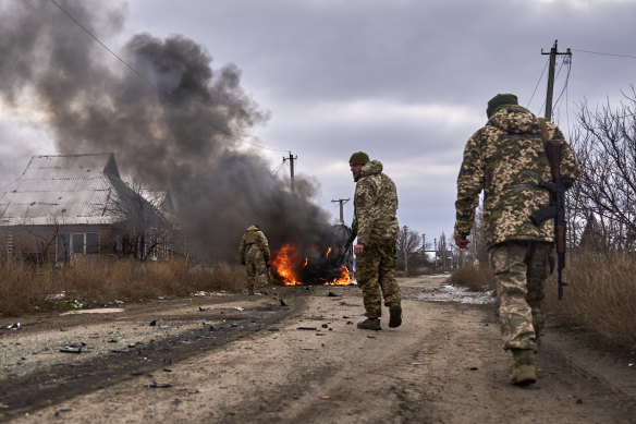 Ukrainian soldiers pass by a volunteer bus burning after a Russian drone hit it near Bakhmut, Donetsk region.