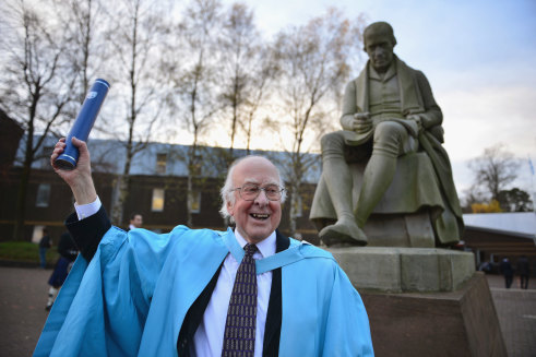 Professor Peter Higgs, poses for photographs in front of a statue of James Watt after receiving an honorary degree of doctor of science, from Heriot-Watt University, Edinburgh, 2012.