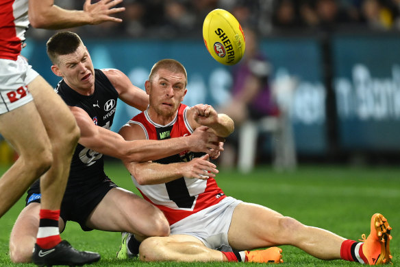 Seb Ross handballs while being tackled by Sam Walsh.