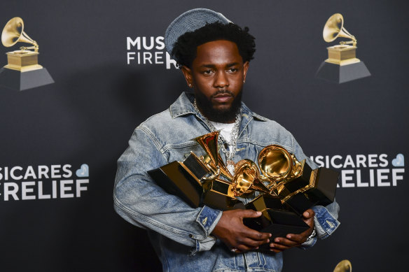 Kendrick Lamar poses in the press room with the award for record of the year, best rap performance, best rap song, best music video and song of the year.