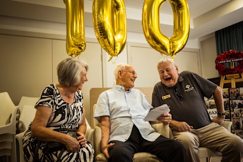 A world away from war: Max Caldwell (centre) at his 100th birthday party in Blackburn. At right is Michael Ralston, son of Gilbert Ralston, a 2/14th Battalion soldier, with Michael’s wife, Elaine.