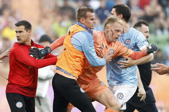 A bleeding Tom Glover of Melbourne City being escorted from the pitch on December 17, 2022.