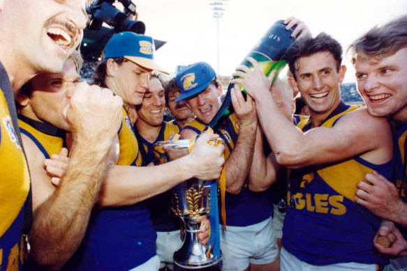 Eagles players celebrate with the premiership cup and champagne.
