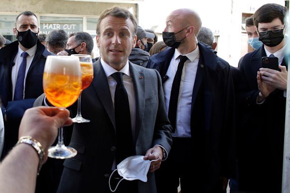 French President Emmanuel Macron, right, and Nevers mayor Denis Thuriot, left, drink with shopkeepers during a visit to mark the reopening of cultural activities after closures during the COVID-19 pandemic, in Nevers, central France.