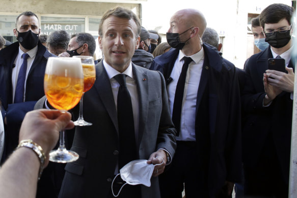 French President Emmanuel Macron, right, and Nevers mayor Denis Thuriot, left, drink with shopkeepers during a visit to mark the reopening of cultural activities after closures during the COVID-19 pandemic, in Nevers, central France.