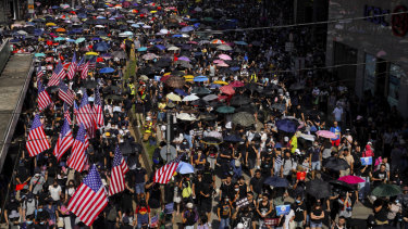 Protesters, some carrying US flags march on a street in Hong Kong.