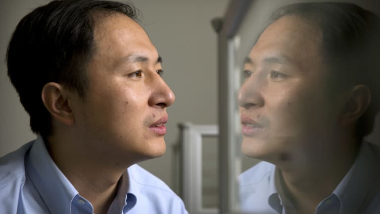 He Jiankui is reflected in a glass panel as he works at a computer at a laboratory in Shenzhen.