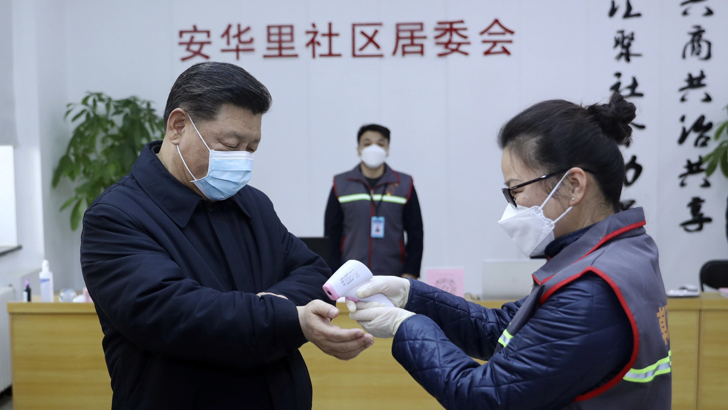 Chinese President Xi Jinping, left, wearing a protective face mask, receives a temperature check as he visits a community health center in Beijing on February 10. 