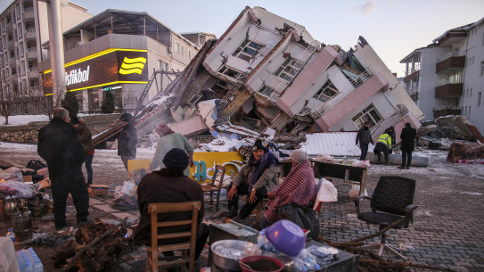 People stand by collapsed buildings in Golbasi, in Adiyaman province, southern Turkey.