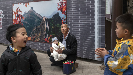 A man holds a baby near other relatives on visit the Great Wall of China last month. The CCP wants families to have more children.