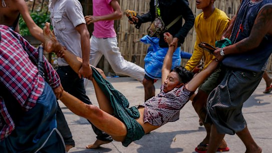 Anti-coup protesters carry an injured man after a clash with riot policemen and soldiers in Yangon, Myanmar.