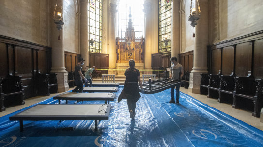 Volunteers place beds in a chapel while building a field hospital at the Cathedral of St. John the Divine, Wednesday, April 8, 2020, in New York. Volunteers assembled and placed 56 beds in five chapels and raised one of several tents in the nave. Work will continue Thursday. (AP Photo/Mary Altaffer)