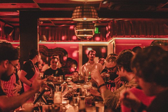 Plentiful seating along the red-hued bar at Herbs Taverne.