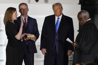 President Donald Trump watches as Supreme Court Justice Clarence Thomas administers the Constitutional Oath to Amy Coney Barrett at the White House in Washington, on Monday night (Tuesday AEDT).