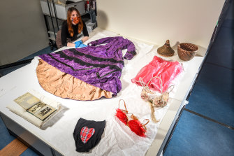 Museums Victoria clothing and textiles collection manager Hannah Perkins with a 19th century purple wedding dress and other items from the collection.