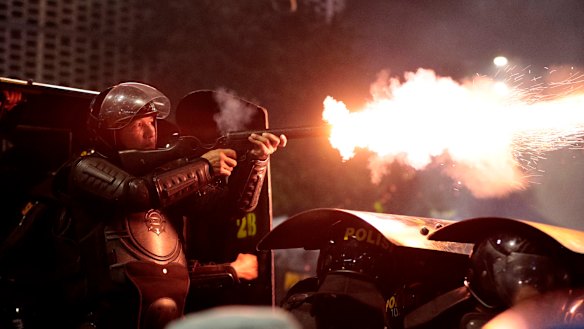 A riot police officer fires his tear gas launcher at supporters of Indonesian presidential candidate Prabowo Subianto during a clash in Jakarta, Indonesia.
