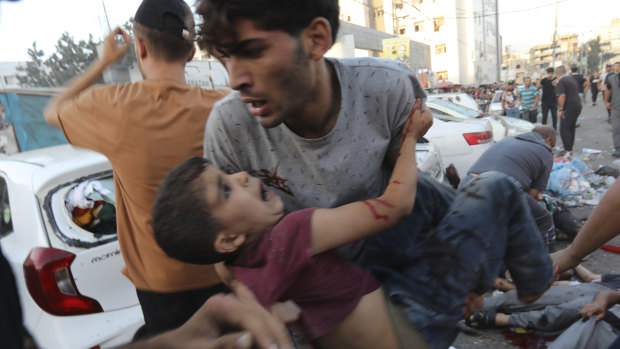 An injured Palestinian boy is carried from the ground following an Israeli airstrike outside the entrance of the al-Shifa hospital in Gaza City.