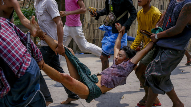 Anti-coup protesters carry an injured man after a clash with riot policemen and soldiers in Yangon, Myanmar.