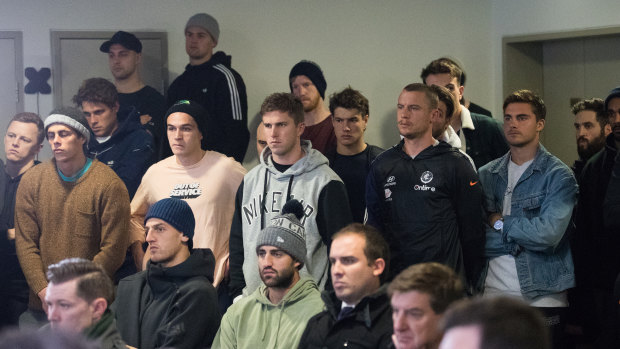 Carlton players watch from the back of the press conference room